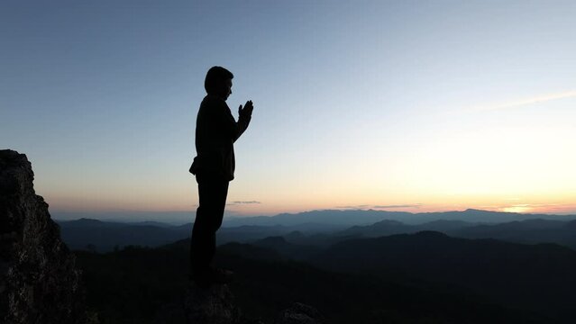Silhouette of a man praying on top of a mountain, prayer of remembrance of god.