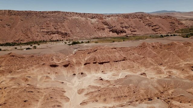 Experience the grandeur of Atacama's desert with stunning drone footage showcasing a small oasis surrounded by massive rock formations.