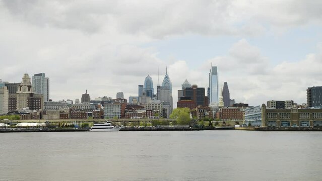 Philadelphia skyline over the calm Delaware River on a cloudy warm day with some traffic on the roads