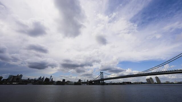 Philadelphia skyline with clouds moving over the calm Delaware River with the Benjamin Franklin Bridge