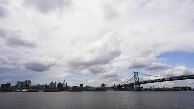 Dark Philadelphia skyline with clouds over the calm Delaware River with the Benjamin Franklin Bridge