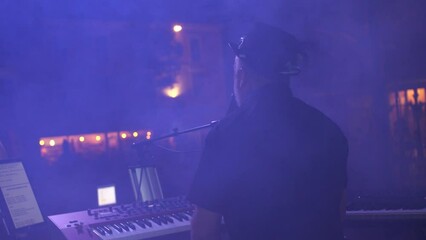 Hand-held shot of a performing on a stage whilst singing and playing the piano