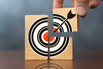 Business target concept of hand putting the jigsaw puzzle last missing piece. Close-up wooden...