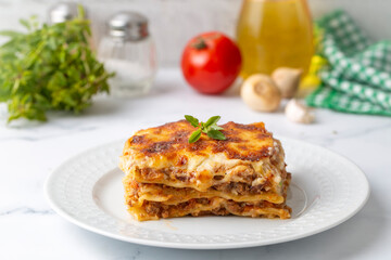 Portion of ground beef lasagna topped with melted cheese and garnished with fresh parsley served on a plate in close view for a menu - obrazy, fototapety, plakaty