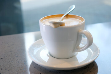 very appetizing coffee foam with spoon quickly stir it in white cup background for any advertising screen saver for music latte coffee with milk with cream restaurant blurred background space for ad