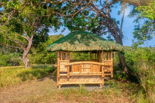 A traditional Filipino bamboo hut with a thatched roof, brand new with varnished wood, used as an outdoor covered sitting and eating area for homes or resort use.