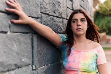 mujer joven adolescente posando en un muro de ladrillos  con ropa de colores urbana en la ciudad.