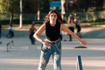 bella mujer joven andando en patines de 4 ruedas en la ciudad al atardecer en un día de verano. - obrazy, fototapety, plakaty