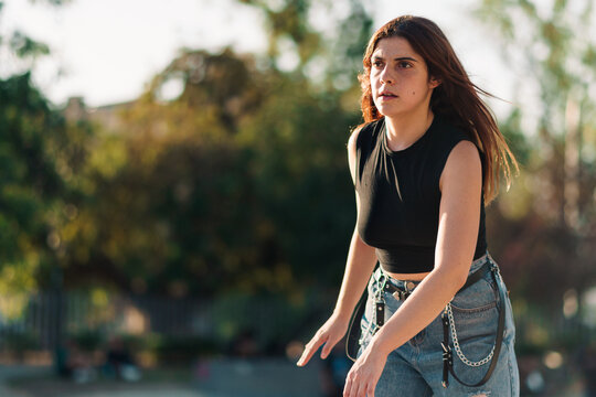 mujer joven adolescente andando concentrada en patines con vista desde cerca en un parque con luz natural