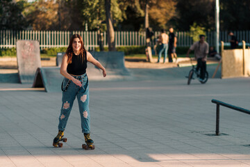 bella mujer joven andando en patines de 4 ruedas en la ciudad al atardecer en un día de verano.