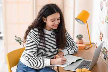 Female student writing in notebook at home