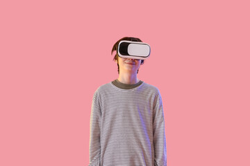 Teenage boy in VR glasses on pink background