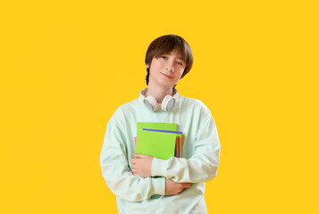 Male student with copybooks on yellow background