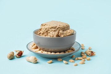 Bowl of tasty halva and peanuts on color background