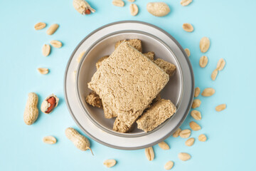 Bowl of tasty halva and peanuts on color background
