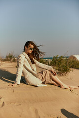 Fototapeta na wymiar a woman on the beach sits in a stylish jacket during her vacation
