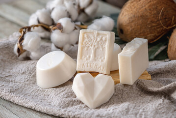 Cute pieces of white natural soap, coconut and cotton on the table
