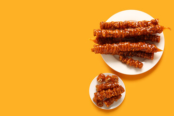 Plates with tasty churchkhela on yellow background