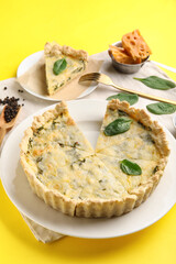 Plates with pieces of delicious quiche on yellow background