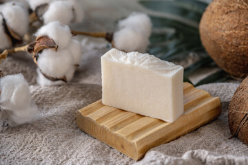 A piece of handmade white natural soap on a wooden soap dish - obrazy, fototapety, plakaty