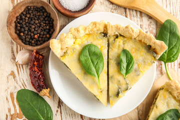Plate with pieces of delicious quiche and peppercorn on white wooden background