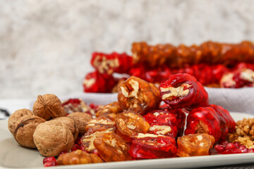 Plate with delicious churchkhela and walnuts on white grunge table