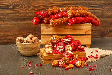 Board with delicious churchkhela and pomegranate on wooden table