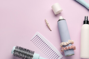 Bottles of hair sprays, comb, brush, scrunchies and pin on color background