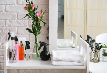 Different hair sprays and towels on table in beauty salon