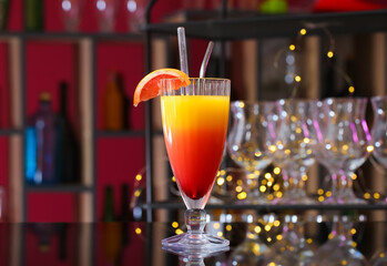 Glass of tasty Tequila Sunrise with grapefruit slice on table in bar
