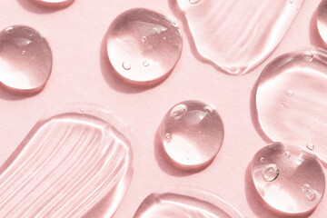 Transparent liquid gel cosmetic texture on a pink background, top view. Aloe vera gel, hyaluronic acid, peptide macro.