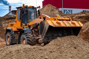 Powerful wheel loader or bulldozer working on a quarry or construction site. Close-up of earthworks. Powerful modern equipment for earthworks.