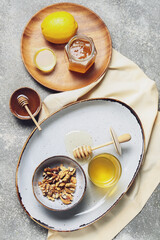 Composition with sweet honey, walnuts and lemon on grey background