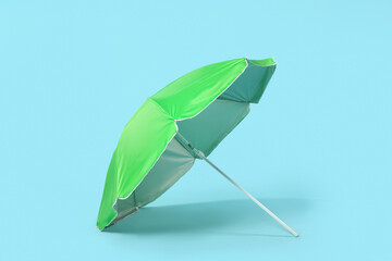 Green beach umbrella on blue background