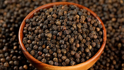 Dried black peppercorns in wooden bowl. Dry seasoning in wooden bowl