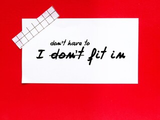 Stick note on red background with handwritten text I DON'T FIT IN, changed to I DON'T HAVE TO FIT IN, to build self acceptance, stop needing others validation and be yourself