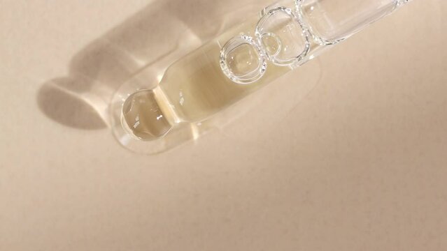 Cosmetic pipette with essential oil for massage close-up on a beige background, top view.