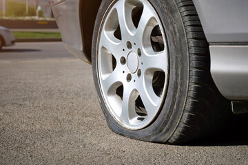 Close-up of a flat tire of a car standing near the road.