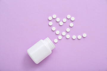 Bottle with heart made of white pills on lilac background