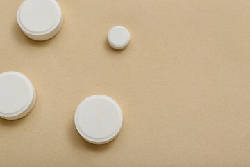 White pills on beige background, closeup