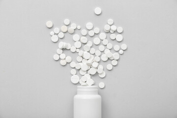 Bottle with white pills on grey background
