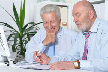 Two old business men sitting at desk and working