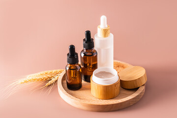 Fototapeta premium Multifunctional moisturizing serum and cream for face and body skin care in a cosmetic set of natural self-care products. Brown background.
