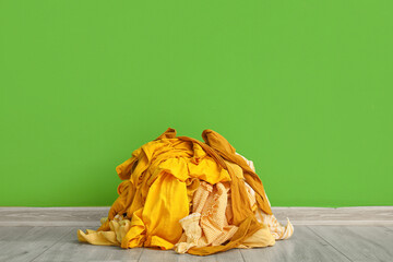 Stack of dirty clothes near green wall