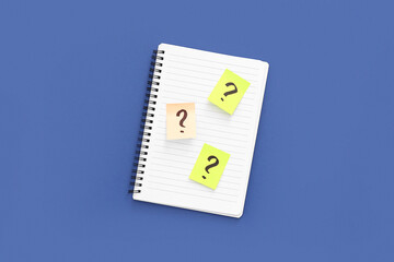 Sticky notes with question marks and notebook on blue background