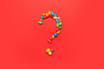 Question mark made of candies on red background