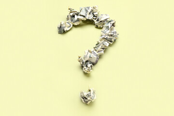 Question mark made of crumpled dollar banknotes on yellow background