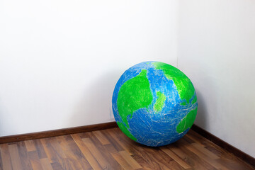 Eco problem. Planet earth in the corner of the room. Surrealism.