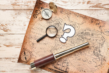 World map with question mark, spyglass, compass and magnifier on white wooden background
