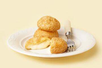 Plate with delicious choux pastry on beige background